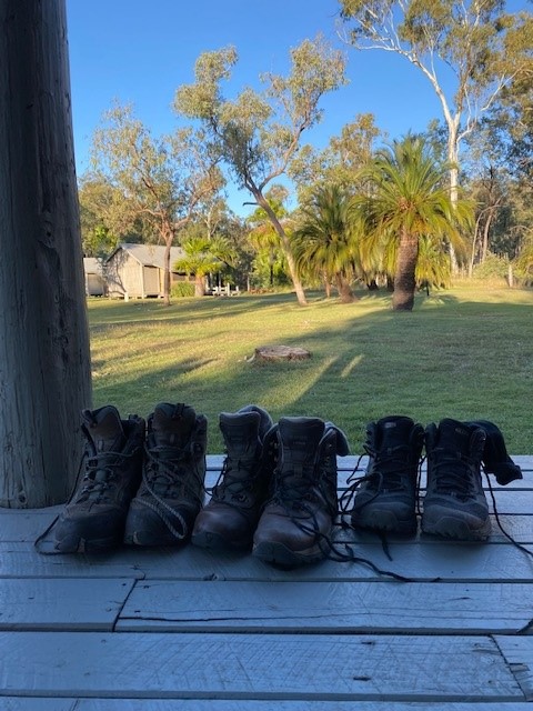 A photo of three pairs of hiking boots lined up at the camp site.