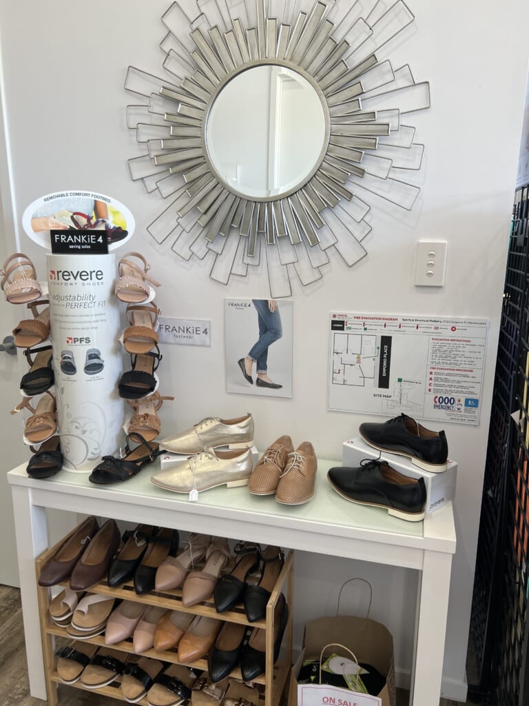 A photo of a table with a stand of Frankie4 shoes and sandles and a mirror