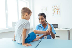 Taking care of children's feet. Female orthopedist examining little child foot condition in clinic.
